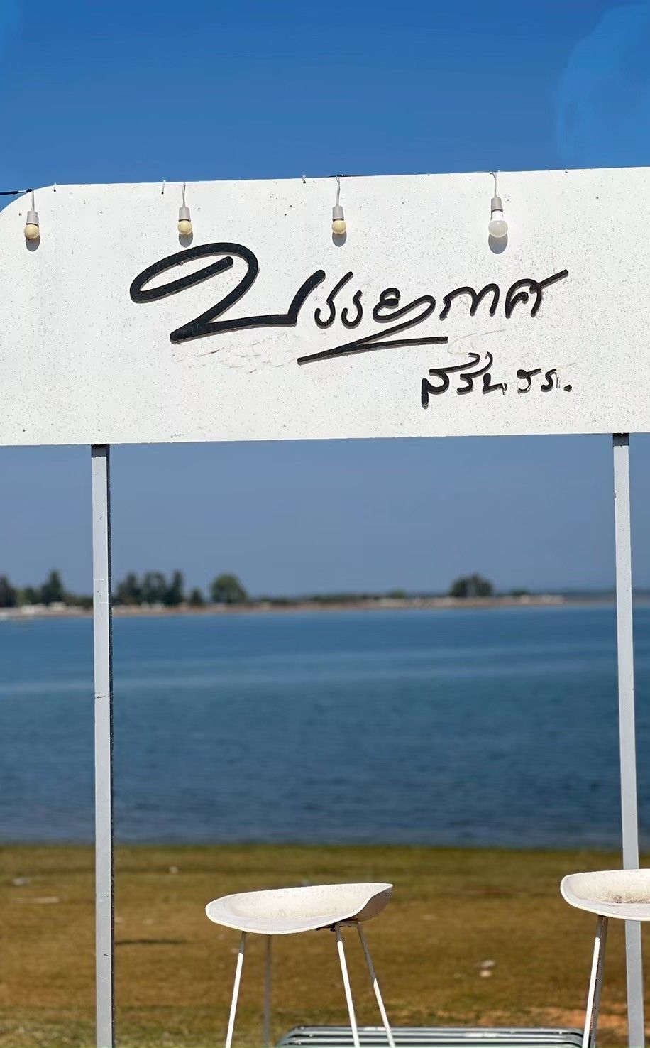 A white structure with the name "Lissemore" and a date "05/05" written on it, overlooking a body of water.