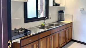 A modern kitchen with wooden cabinets, a stainless steel sink, and a window above the sink. - Cosy Farmstay Tuvurara Savusavu (Nakasa)