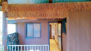A wooden building with a thatched roof, a stone wall, and a window. - Cosy Farmstay Tuvurara Savusavu (Nakasa)