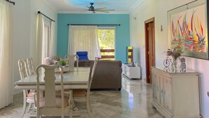 Un vaste espace de vie doté d’un haut plafond, comprenant une table à manger avec des chaises, un canapé et un meuble agrémenté d’objets décoratifs.