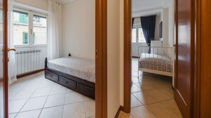 A bedroom with a bed, a radiator, a window with curtains, and a door leading to another room. - Gabriella by Interhome (Rapallo)