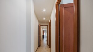 A hallway with wooden doors and white walls, leading to a room with a window. - Gabriella by Interhome (Rapallo)