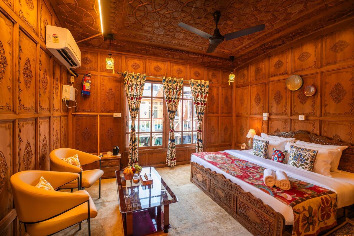 Quarto de madeira com uma cama, duas cadeiras, uma mesa e um ventilador de teto.