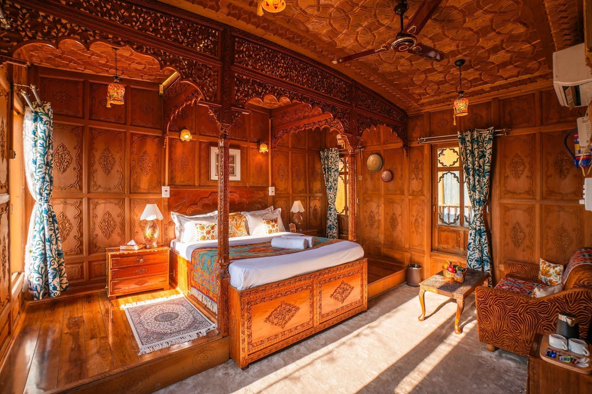 Quarto tradicional com cama de dossel, paredes de madeira e detalhes elaborados no teto.