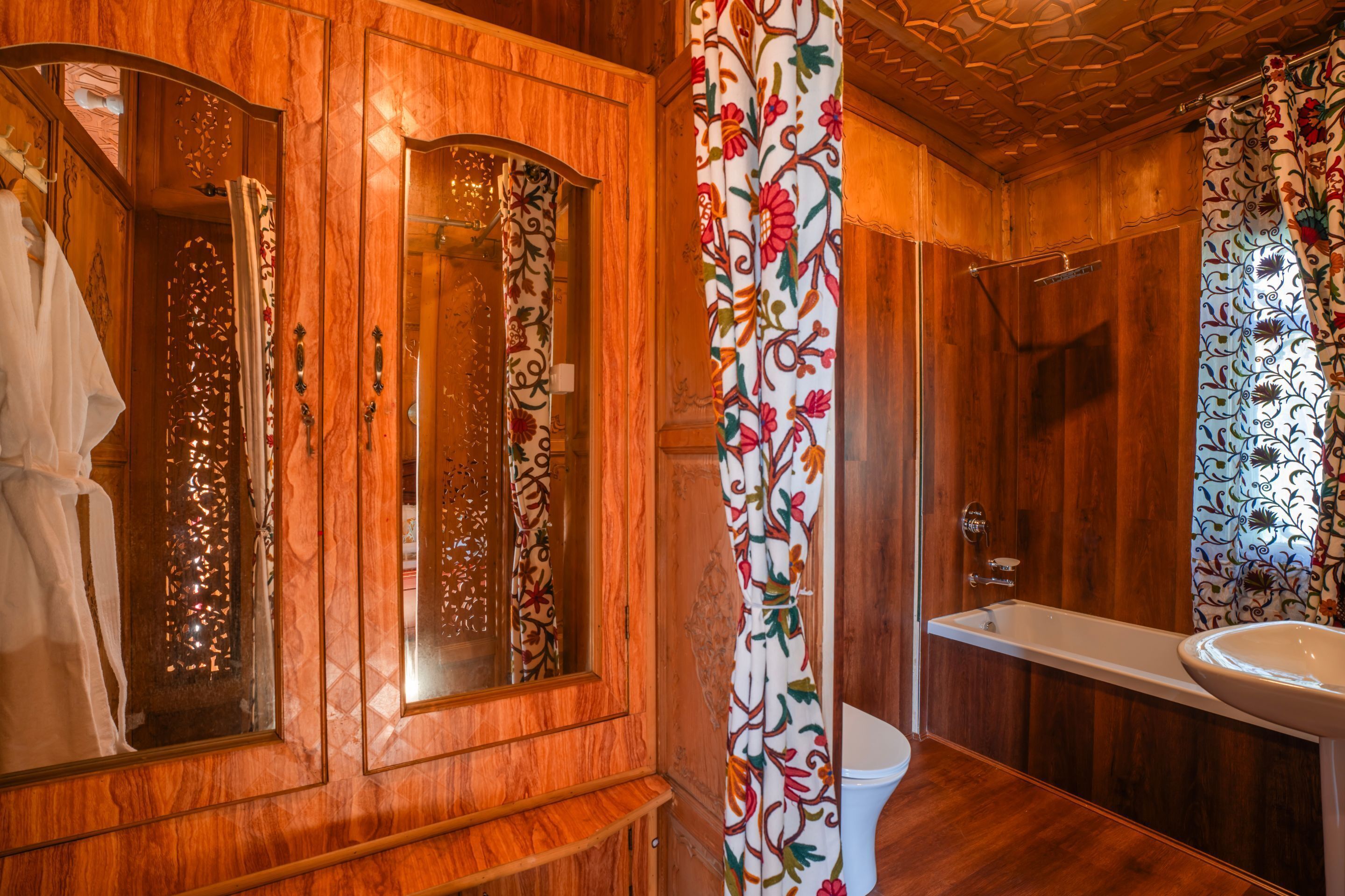 A wooden bathroom with a large mirror, a toilet, and a bathtub.