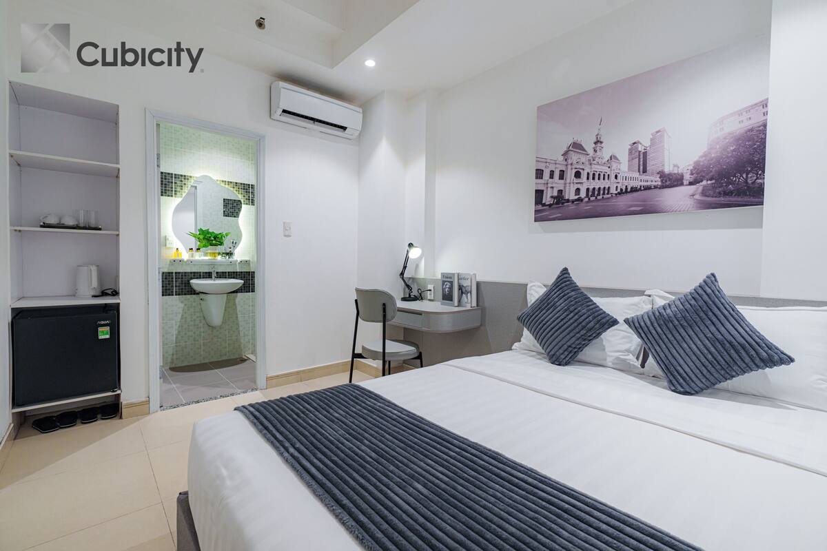 Une chambre d’hôtel comprenant un lit, un bureau, une chaise, une petite kitchenette et une salle de bain.