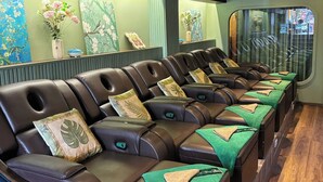 A row of massage chairs with green towels, a wooden floor, and artwork on the walls. - Cubicity De Tham (Ho Chi Minh City)