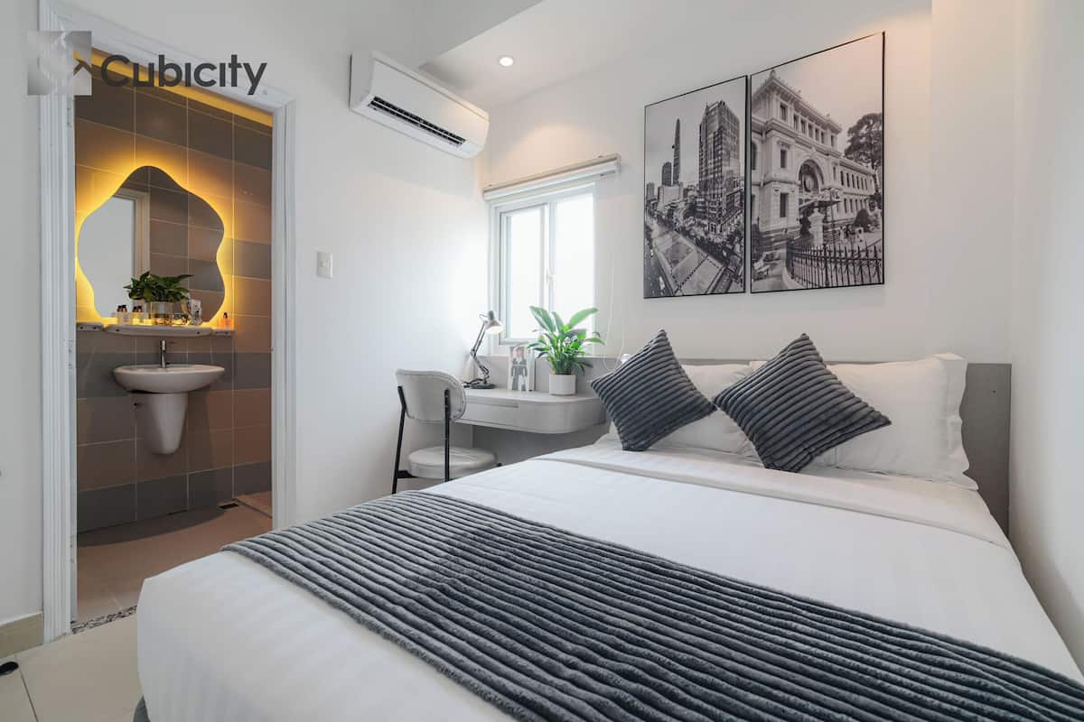 Une chambre d’hôtel moderne avec un lit, une table de chevet et une grande fenêtre.