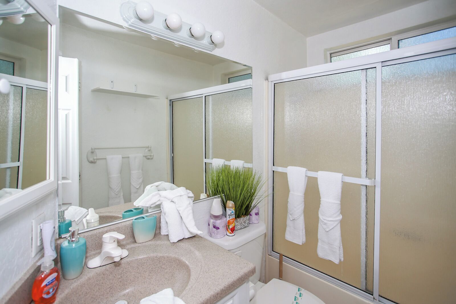 Un baño con lavamanos, espejo y perchero para toallas.