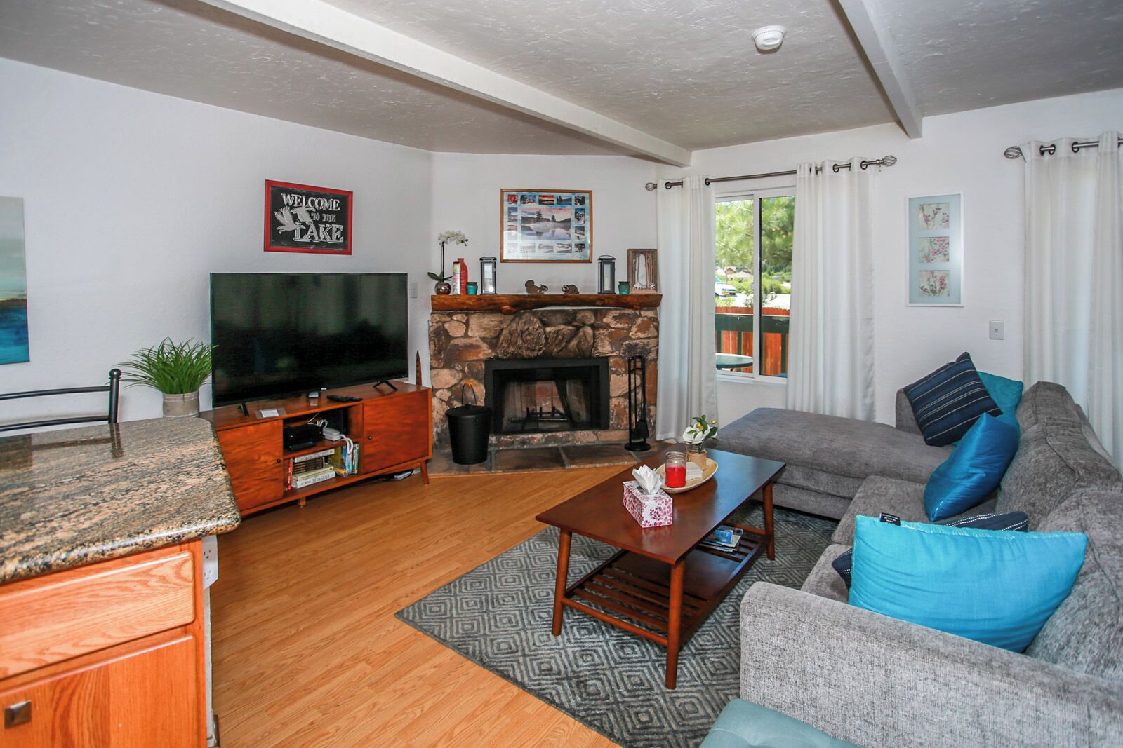 Ein Wohnzimmer mit Kamin aus Stein, Fernseher, Sofa und Couchtisch.
