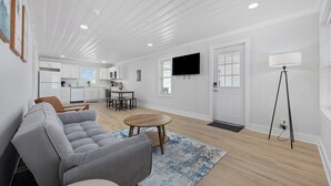 A modern living room with a gray sofa, a wooden coffee table, and a kitchen in the background. - Bright 2BR Surf Hideaway | 1-Min Walk to Waves (North Myrtle Beach)