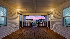 A covered wooden deck with a view of houses in the background. - Bright 2BR Surf Hideaway | 1-Min Walk to Waves (North Myrtle Beach)