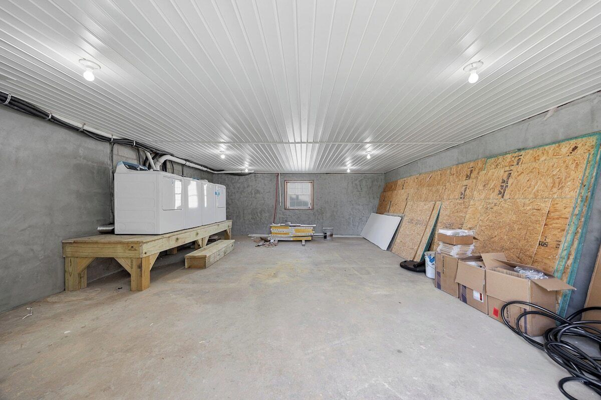 Een kamer met een betonnen vloer, houten wanden en een plafond met inbouwverlichting.