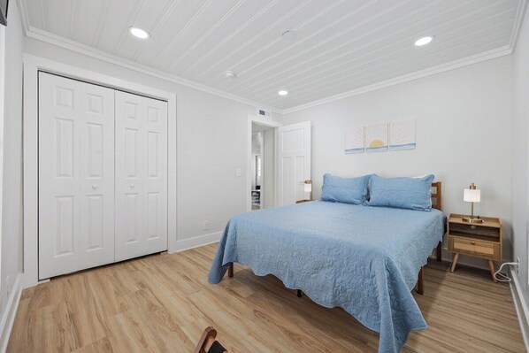 A bedroom with a bed, nightstands, a wooden floor, white walls, and a ceiling with recessed lighting. - Modern 2BR Surf Condo | 1-Min Beach Walk (North Myrtle Beach)