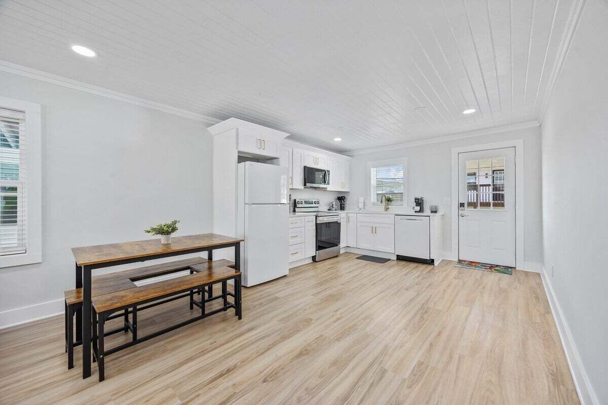 Una cocina moderna con armarios blancos, una mesa de comedor de madera y un horno empotrado.