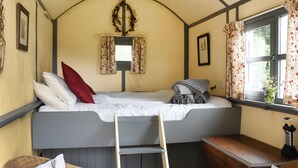 A cozy room with a bed, a desk, and a chair. There are two windows with curtains, a ladder, and a wall-mounted decoration. - Brown Hare - UK49799 (Brecon)