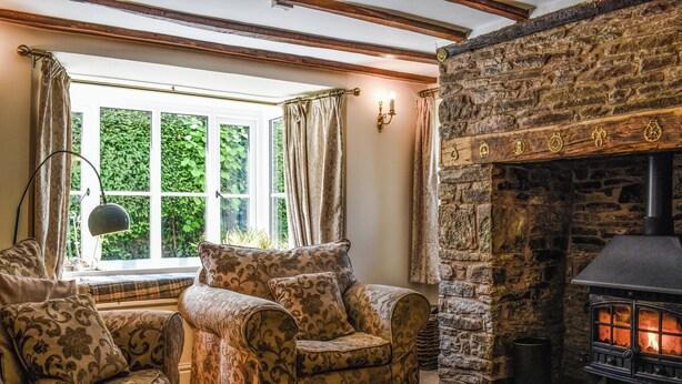 A cozy room with a stone fireplace, a sofa set, and a large window with curtains. - 4 bedroom accommodation in Clifford, near Hay-on-wye (Clifford, near Hay-on-wye)