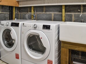 A laundry room with two front-loading washing machines and a sink.
