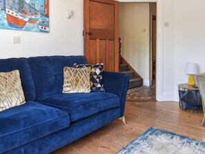 Un canapé bleu orné de coussins à motifs, une porte en bois et un escalier menant à une autre pièce.