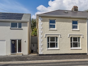 Two adjacent houses with distinct architectural styles, one with a solar panel roof and the other with a traditional pitched roof.