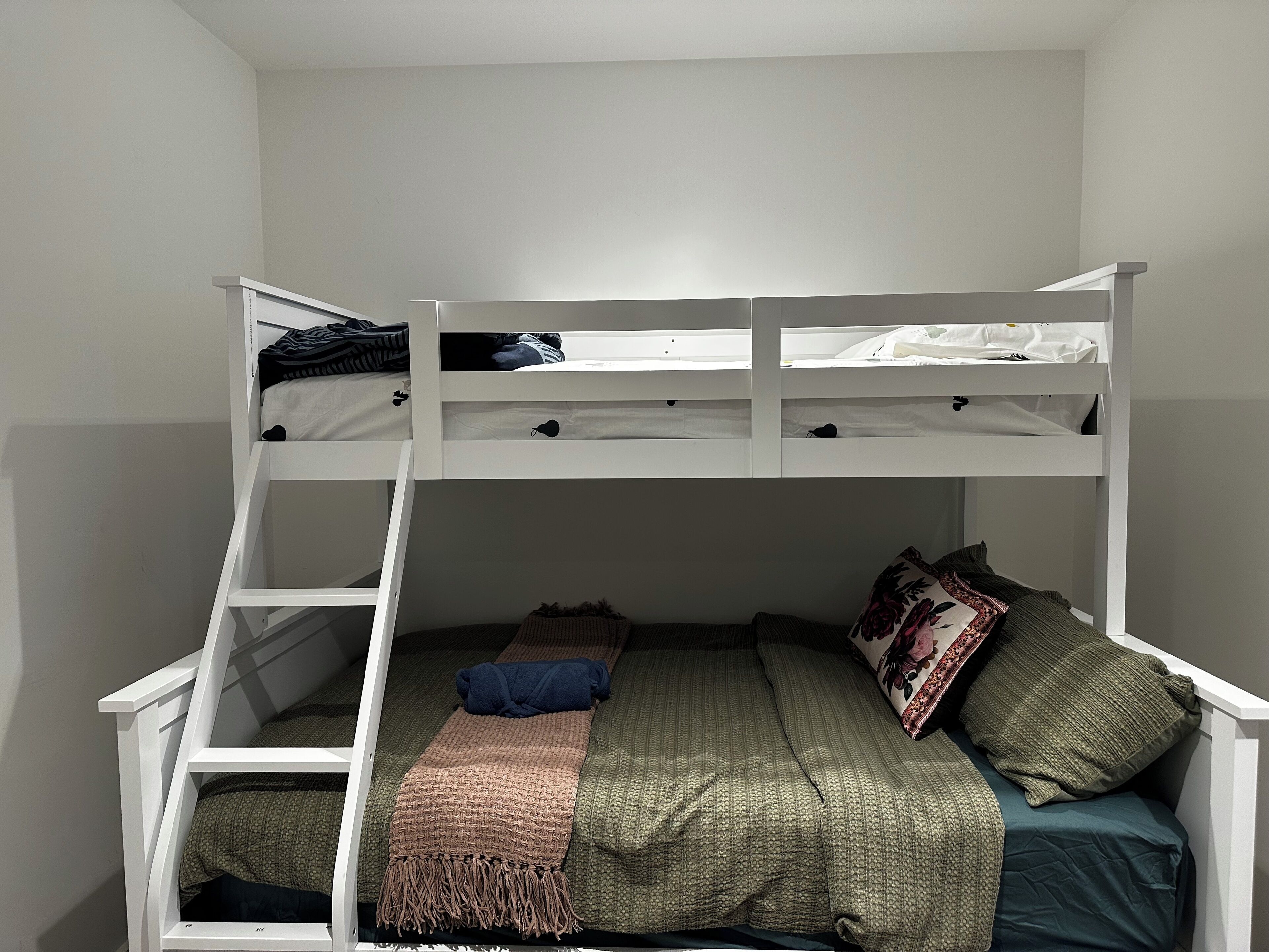 Un letto a castello con scala, un letto singolo in basso e un piccolo comodino.