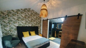 Una camera da letto con un letto, una sedia, un lampadario e una porta scorrevole che dà accesso a un bagno.