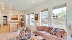 A spacious living room with a large window, a sofa, a coffee table, and a patterned chair. - Walk to Southern Utah Campus: Home w/ Fire Pit (Cedar City)