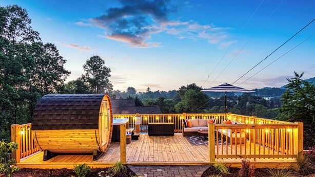 A wooden deck with a seating area, a small structure, and a view of the surrounding landscape.