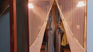 A room with a bed, a chair, and a hanging garment rack.