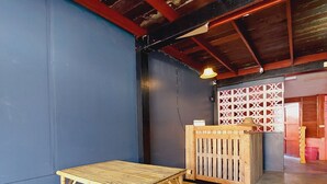 A room with a blue wall, a wooden table and bench, a wooden partition, and a ceiling with exposed beams.