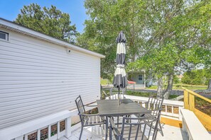 A patio with a table and chairs, an umbrella, and a white building. - 2 Blocks to Crystal Coast: Family-Friendly Retreat (Harkers Island)