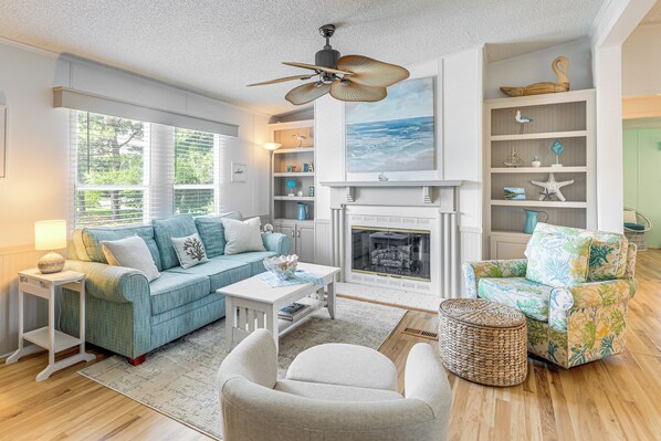 A living room with a sofa, armchairs, a coffee table, a fireplace, and a ceiling fan. - 2 Blocks to Crystal Coast: Family-Friendly Retreat (Harkers Island)