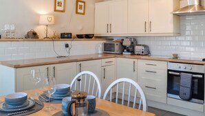 A modern kitchen with white cabinets, a wooden countertop, and a dining area with a table set for two.