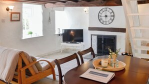 A dining area with a wooden table, chairs, and a menu. There is a television and a fireplace in the background.