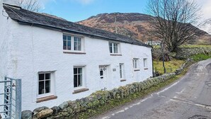 A white building with multiple windows and a stone wall in front.