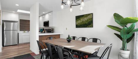 A modern kitchen with white cabinets, a stainless steel refrigerator, and a wooden countertop.