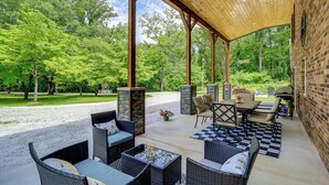 Een terras buiten met rieten meubels, een geruite vloer en een bakstenen muur.