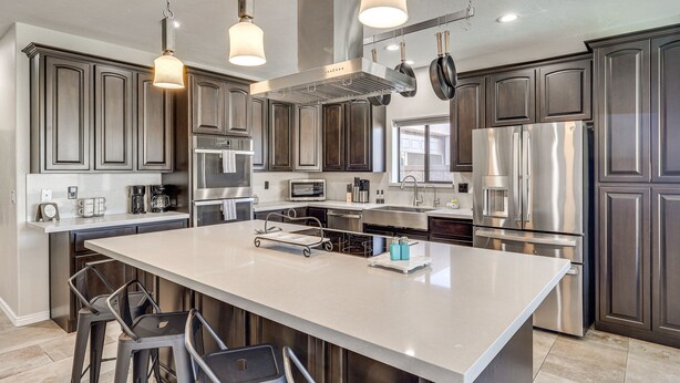 A modern kitchen with dark wood cabinets, stainless steel appliances, and pendant lighting. - Pet-Friendly LHC Home w/ Temp-Controlled Pool! (Lake Havasu City)