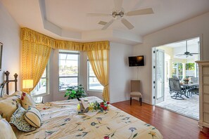 A bedroom with a bed, a television, a chair, and a view of the patio. - Pool, Spa & Dock: Waterfront Tarpon Point Home (Cape Coral)
