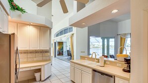 A spacious kitchen with white cabinets, a dishwasher, and a large window providing natural light. - Pool, Spa & Dock: Waterfront Tarpon Point Home (Cape Coral)