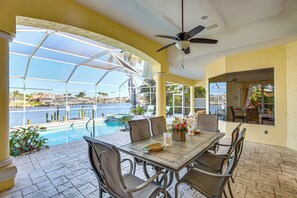 A covered outdoor dining area with a view of a swimming pool and a marina. - Pool, Spa & Dock: Waterfront Tarpon Point Home (Cape Coral)