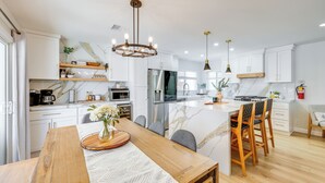 A modern kitchen with white cabinetry, a marble island, and pendant lighting. - Walk to The Village Shops/Eats: Big Bear Lake Home (Big Bear Lake)