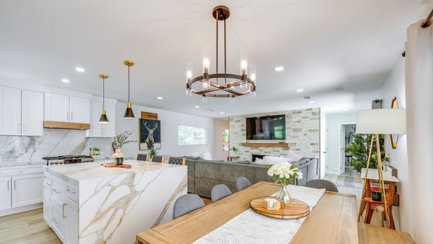 A modern kitchen with white cabinets, a marble island, and a wooden dining table. - Walk to The Village Shops/Eats: Big Bear Lake Home (Big Bear Lake)