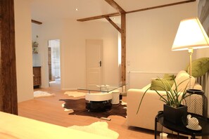 A modern living room with a glass coffee table, white sofa, and a lamp.