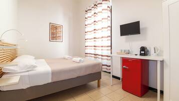 Habitación de hotel con una cama, un escritorio con un armario rojo, un televisor y una cortina de ducha.