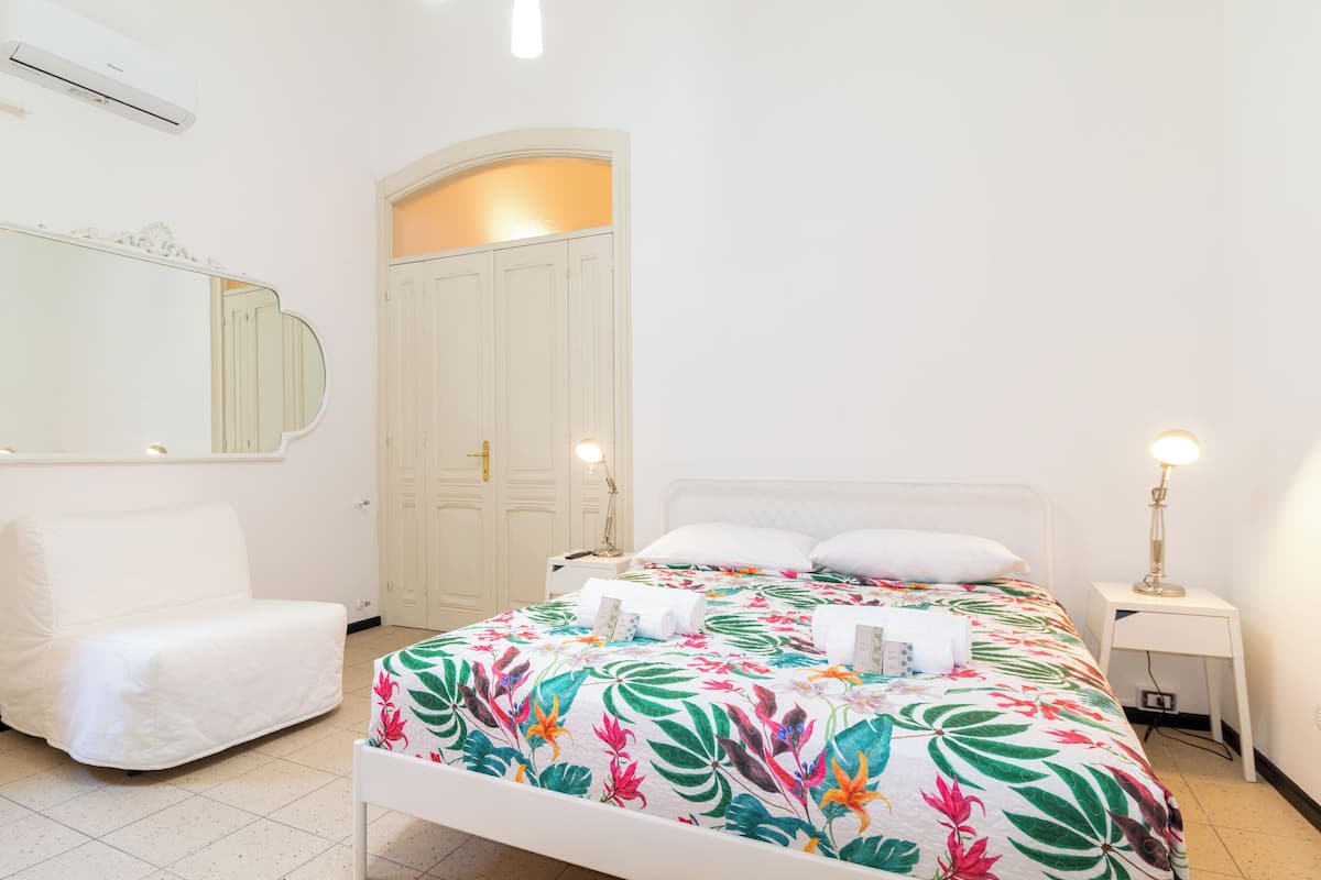Une chambre d’hôtel comprenant un lit, une chaise, une table de chevet, un miroir et une armoire.
