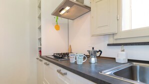 Une cuisine moderne équipée d’une cuisinière à gaz, d’une machine à café et de deux tasses posées sur le comptoir.