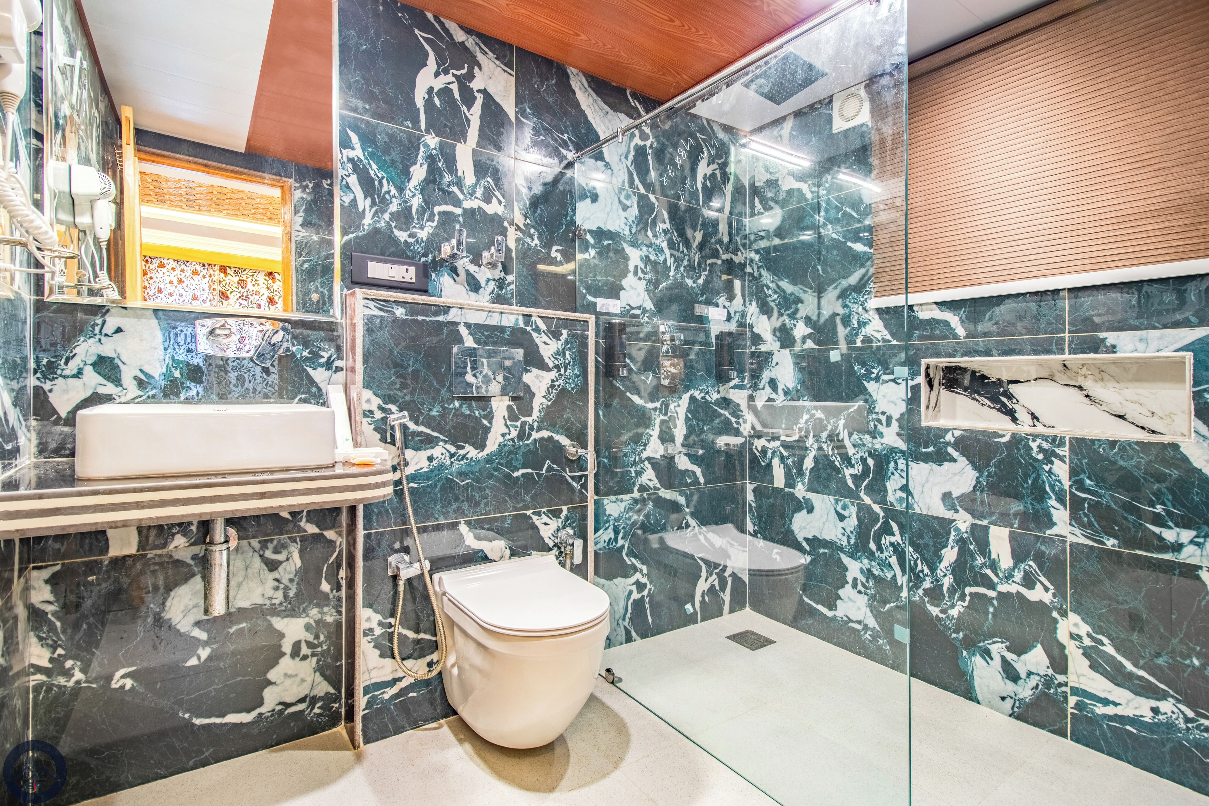 Un baño moderno con salpicadero de mármol, inodoro blanco y cabina de ducha de vidrio.