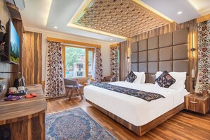 A bedroom with a large bed, a desk, a chair, a TV, and a view of the outside. - Bombay Residency (Pahalgam)