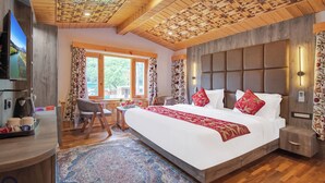 A spacious bedroom with a large bed, wooden ceiling, and a view of greenery outside. - Bombay Residency (Pahalgam)
